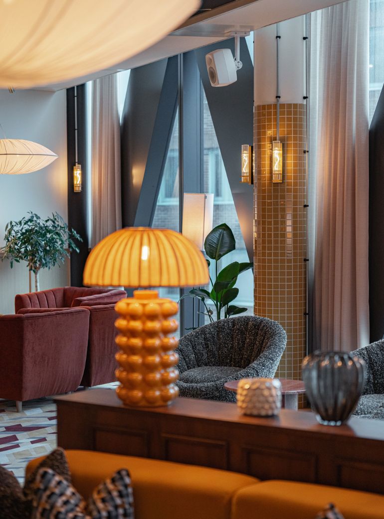 Elegant lounge med mjuk belysning, växter och ljudlösningar diskret integrerade i inredningen för en behaglig atmosfär.