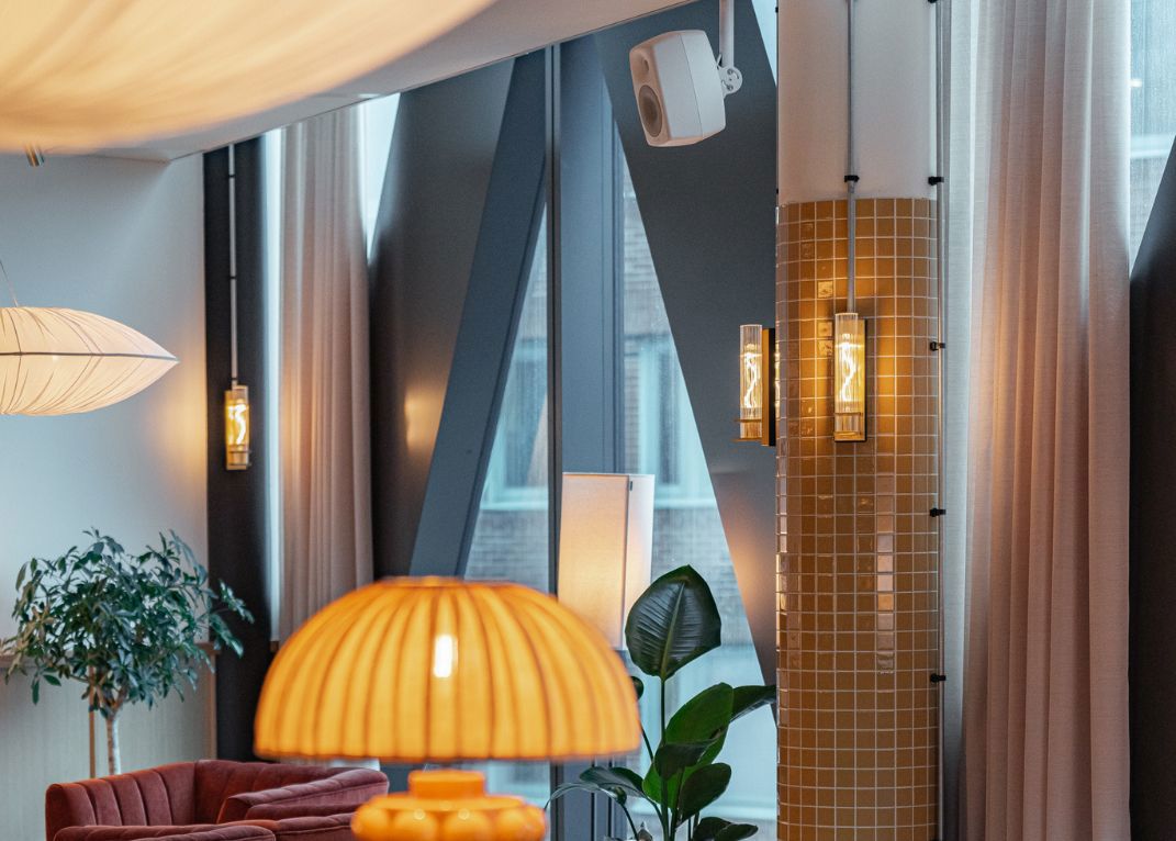 En modern lounge med elegant belysning, växter och ljudlösningar integrerade i inredningen för en stilren och funktionell miljö.